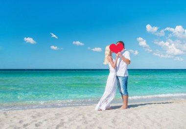 Loving couple at sunny sea beach with red heart clipart
