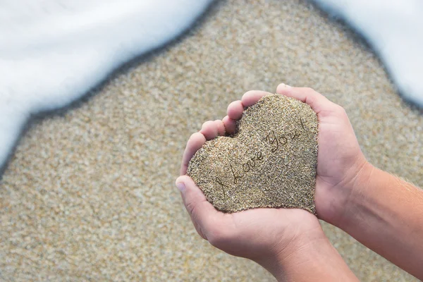 "Seni seviyorum metin ile kalp şeklinde bir kum tutan eller" — Stok fotoğraf