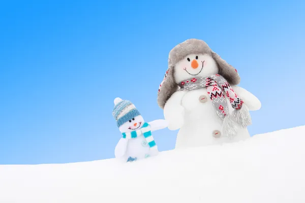 Happy winter snowmen family or friends against blue sky — Stock Photo, Image
