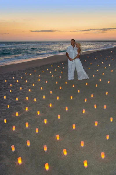 Casal apaixonado na praia do mar em velas contra o pôr do sol brilhante — Fotografia de Stock