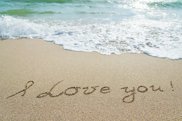 Palabras "Te amo" esbozan en arena mojada con brillo de ola — Foto de Stock