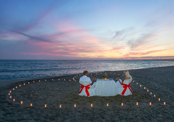 Lovers couple have a romantic dinner with heart of candles — Stock Photo, Image