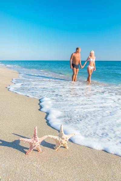 Älskande par på sandig strand med starfishes — Stockfoto