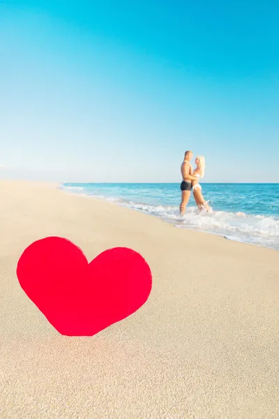 Pareja en la playa del mar y gran corazón rojo —  Fotos de Stock