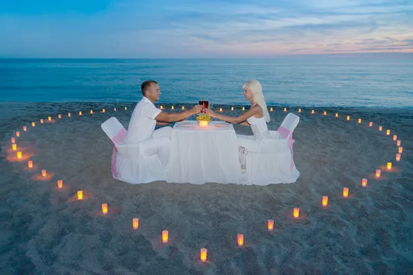 Coppia in spiaggia cena romantica con candele cuore — Foto Stock