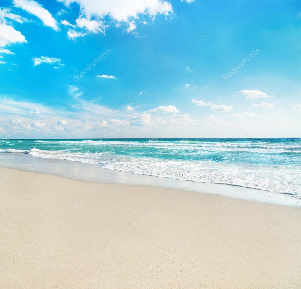 Sea beach against wave foam and blue sunny sky