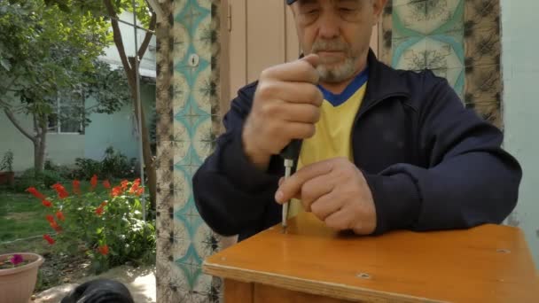 Een man verwijdert een schroefschroef met een schroevendraaier. — Stockvideo
