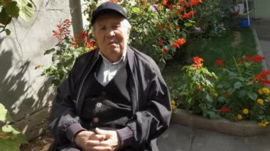 Yaşlı bir adam bahçesinde oturuyor..