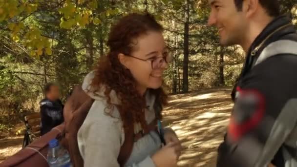 Girl hiker in camp standing, smiling and drinking from a pipe. — Stock Video