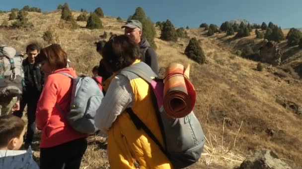 Un grupo de turistas descansa y comienza a escalar la montaña. — Vídeos de Stock