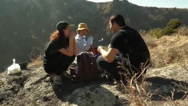 En una parada en las montañas, tres turistas beben agua. Video de stock libre de derechos