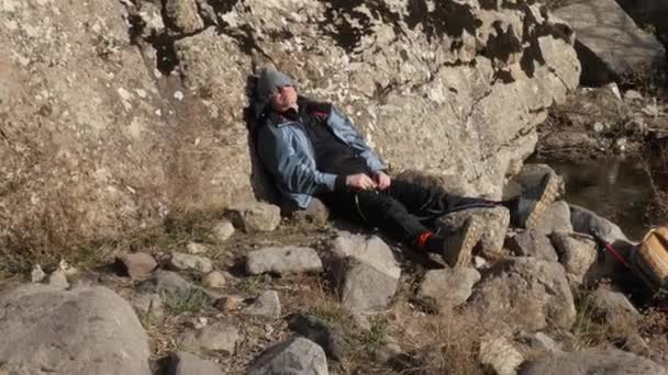 Un escursionista dorme appoggiato ad una roccia. Clip Video