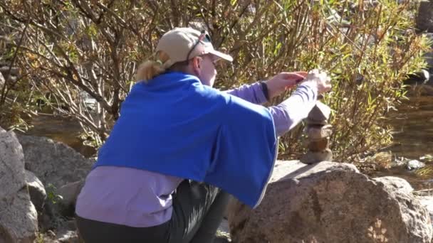 Egy kis kövekből piramist építő nő — Stock videók