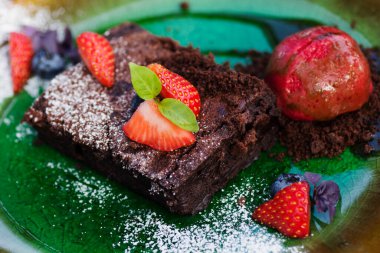 Taze çilekli çikolatalı pasta ve yeşil tabakta lezzetli dondurma..