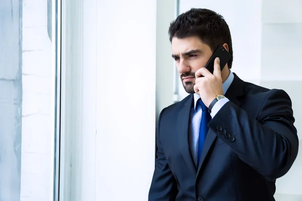 Empresário olhando pela janela e falando ao telefone — Fotografia de Stock