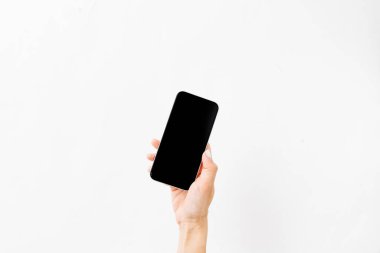 Beyaz arka planda siyah bir akıllı telefon tutan bir kadın.