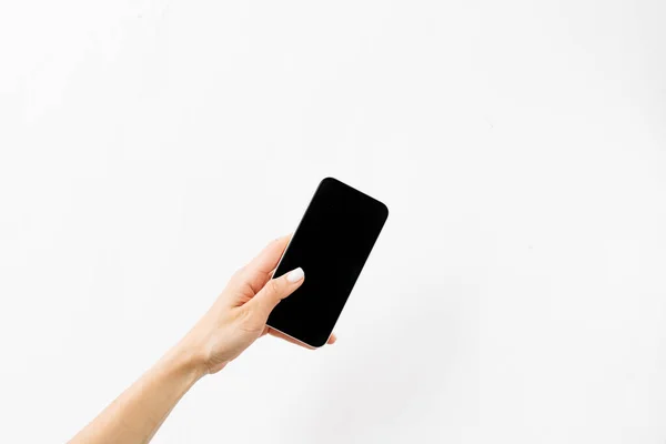 Vrouwelijke Hand Met Een Zwarte Smartphone Een Witte Achtergrond — Stockfoto