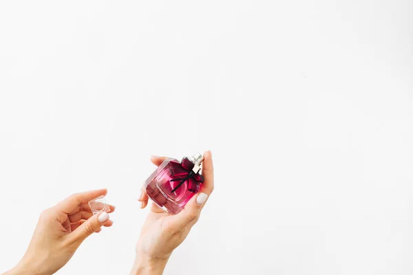 白い背景にピンクの香水瓶を持っている女性の手 — ストック写真