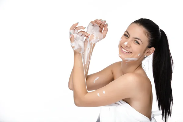 Bellissimo viso di giovane donna con crema cosmetica su una guancia. Ritratto da primo piano isolato su bianco . — Foto Stock