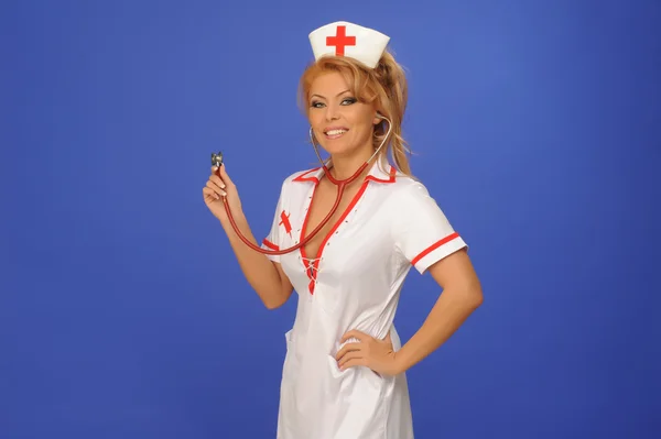 Sexuelle Frau im Krankenschwesteranzug mit Stethoskop-blauem Hintergrund — Stockfoto