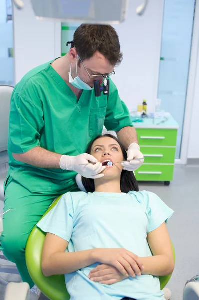 Dentista cura uma paciente do sexo feminino — Fotografia de Stock