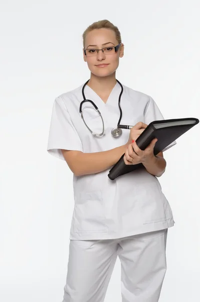 Bela enfermeira sorrindo e tomando notas em um backgroun isolado branco — Fotografia de Stock