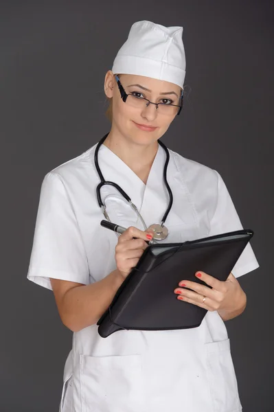 Frumoasă asistentă zâmbind și luând notițe pe un backgroun alb izolat — Fotografie, imagine de stoc