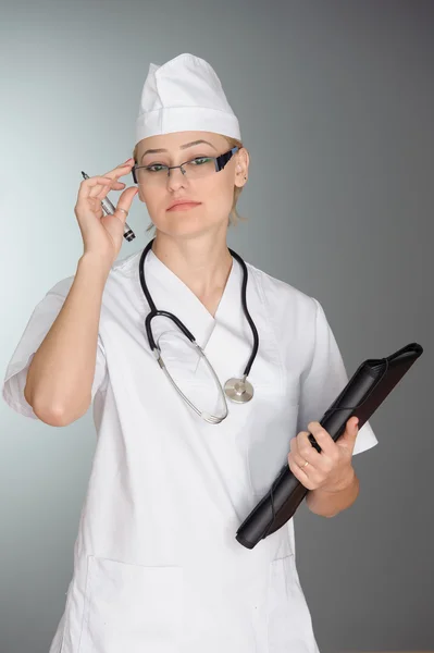 Schöne Krankenschwester lächelt und macht Notizen auf einem weißen isolierten Hintergrund — Stockfoto