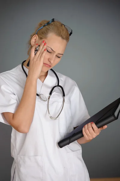 Schöne Krankenschwester lächelt und macht Notizen auf einem weißen isolierten Hintergrund — Stockfoto