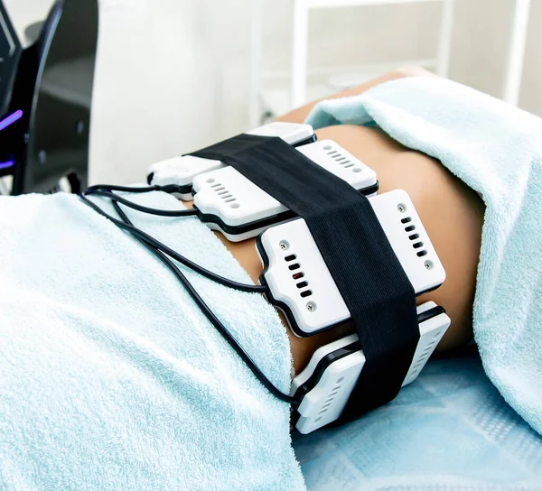 In a beauty salon, a girl performs a hardware procedure for weight loss laser lipolysis. Figure correction by hardware methods