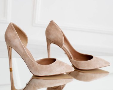 Süet bej topuklular. Çıplak topuklular aynanın üzerinde duruyor. Şık ve şık ayakkabılar ve topuklular..