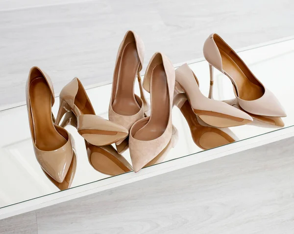 Three pairs of stilettos - patent, leather and suede. Nude stilettos stand on the mirror. Fashionable and stylish shoes and heels.