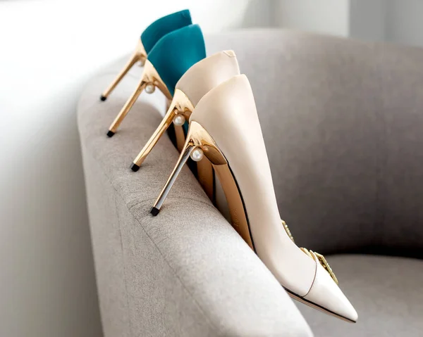 Beautiful beige and green silk shoes. Nude and turquoise heels for a wedding with gold decoration stand on a gray chair