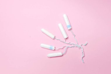 Birçok hijyenik tampon açık pembe arka planda bir sırada yatar. Adet döngüsü ve hamilelik. Negatif hamilelik testi ve doğum kontrol hapları.