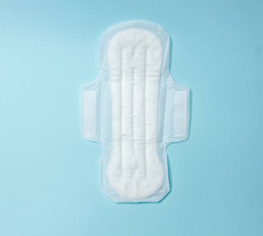 Açık mavi arka planda hijyenik pedler var. Adet döngüsü ve hamilelik. Negatif hamilelik testi ve doğum kontrol hapları.