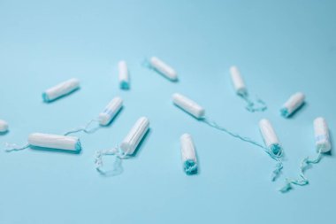 Açık mavi arka planda çeşitli hijyenik tamponlar bulunur. Adet döngüsü ve hamilelik.