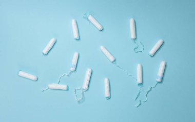 Açık mavi arka planda çeşitli hijyenik tamponlar bulunur. Adet döngüsü ve hamilelik.