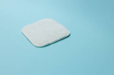 Açık mavi arkaplanda beyaz pamuk ve bambudan yapılmış pamuk. Kozmetik, makyaj ve hijyen için pamuklu bez.