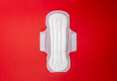 Kırmızı arka planda hijyenik ped var. Adet döngüsü ve hamilelik. Negatif hamilelik testi ve doğum kontrol hapları. Hijyenik peçete.