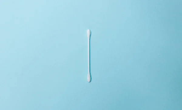 A white cotton swab on a light blue background. Ear stick and cotton swab for cosmetology and hygiene. White cotton buds