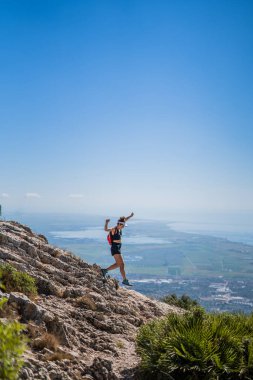 Dağın tepesinde vizörüyle koşan sarışın, beyaz bir kadın.