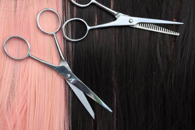 Siyah ve pembe saç arka planında saç kesme makası.