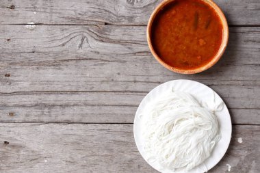 Tahta arka planda pirinç erişteli Tayland körisi.