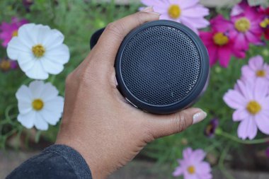 Bluetooth speaker on hand and pink flowers