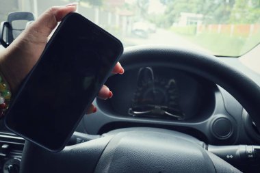 Arabada akıllı telefon kullanan bir kadın.