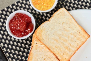 Kahvaltıda kızarmış ekmek, portakal reçeli ve çilek reçeli.