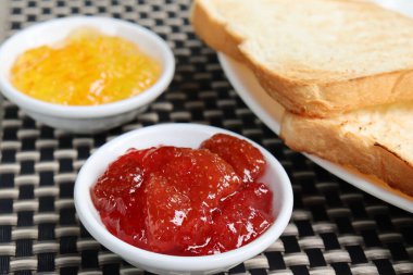 Kahvaltıda kızarmış ekmek, portakal reçeli ve çilek reçeli.