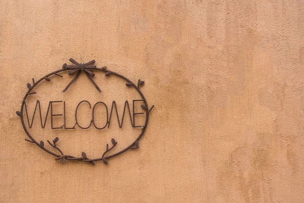 Steel cast welcome sign on earth tone cement wall — Stock Photo, Image