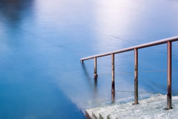 Treppe hinunter ins blaue Wasser Stockbild