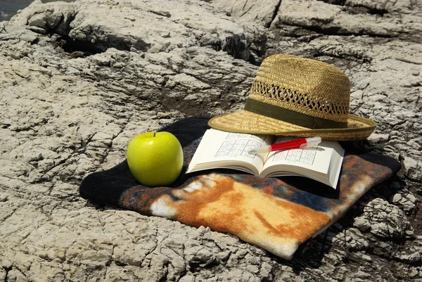 On the cliff book, hat and apple — Stock Photo, Image